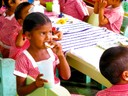 Nursery school children enjoy a snack of peanut butter on cassava bread in Aranaputa, Guyana.The peanuts they are eating were provided by farmers in the region, supported by the Peanut and Mycotoxin Innovation Lab. Local cottage industries processed the peanuts, turning them into peanut butter for the children to eat at school.This program was set up in seven villages throughout the region, serving 1,400 school kids one snack per day. Due to the success of the project, this has been expanded to 47 villages and now serves 4,300 children per day (Feed the Future)